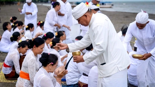 Balinese Hindu ceremony with people in traditional white clothing receiving holy water blessing