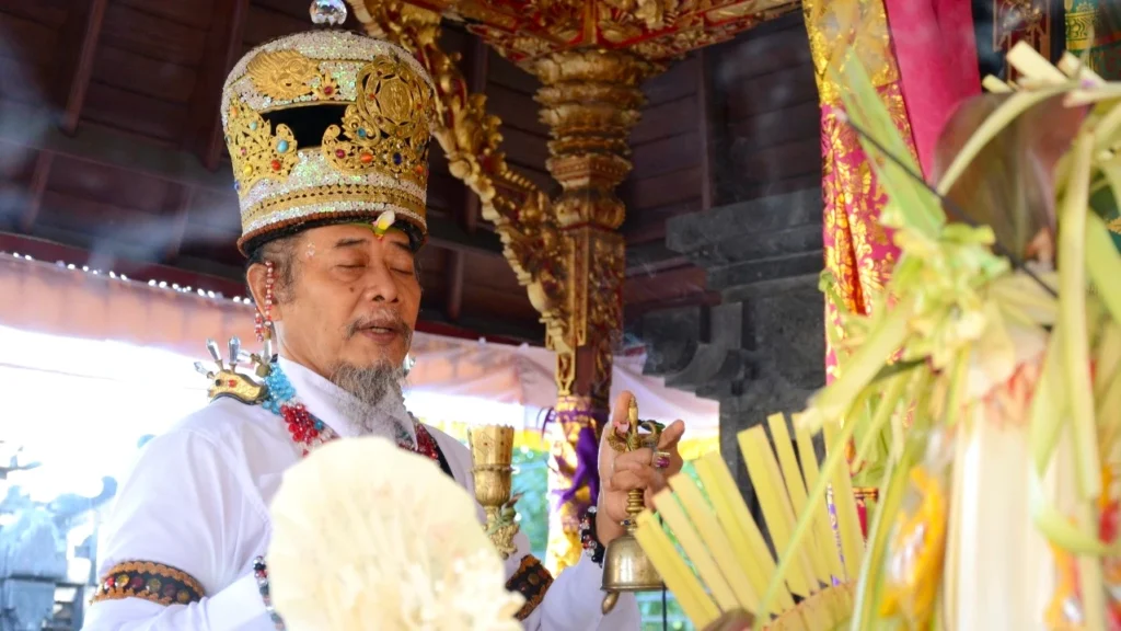 Balinese Hindu priest performing a ritual in a temple with traditional attire