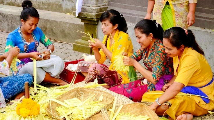 Balinese women preparing traditional offerings together in a community activity