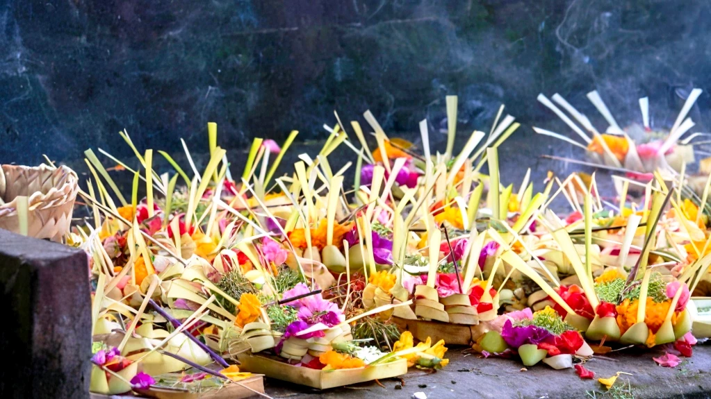 Balinese canang sari offerings placed on the ground with flowers and incense