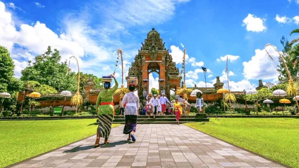 Balinese people walking toward a temple entrance carrying offerings during a traditional ceremony in Bali